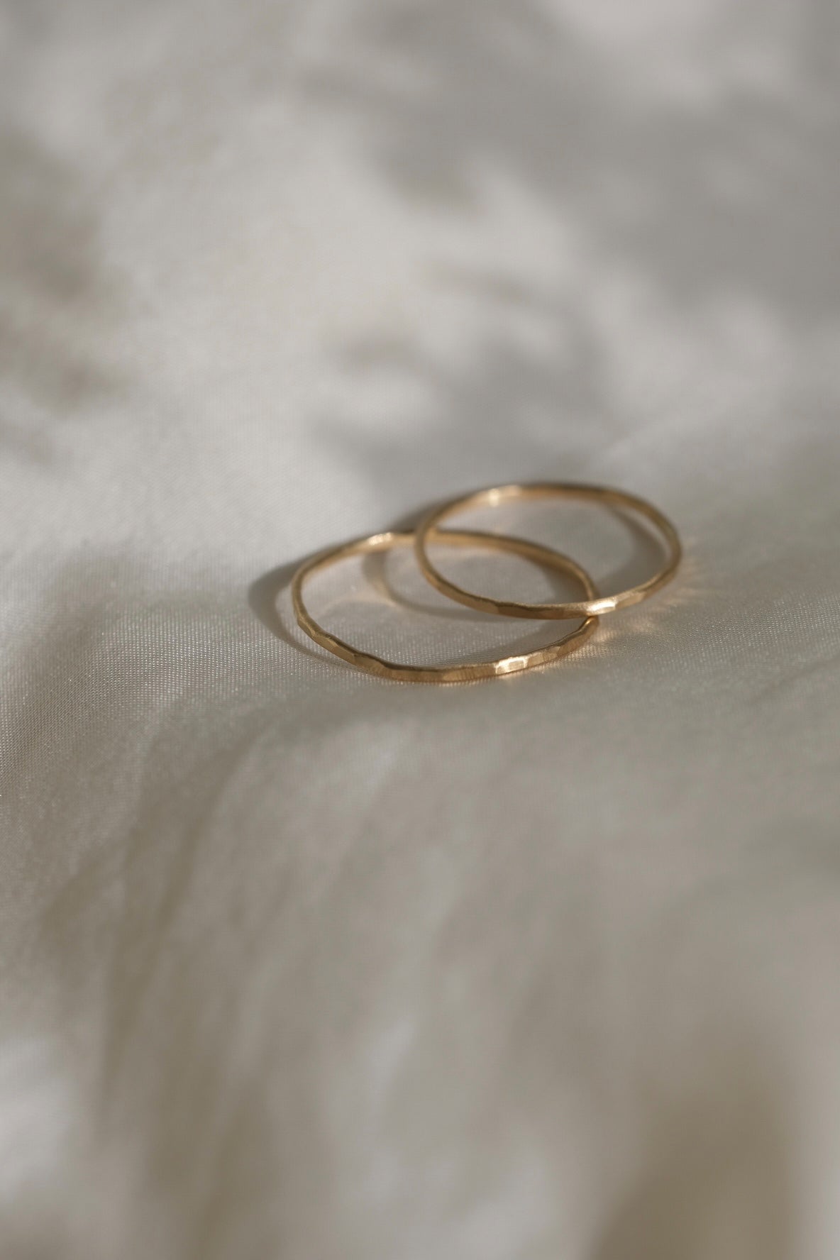 Handcrafted TALLULAH rings in 18k recycled gold on soft fabric, showcasing organic design from Basel, Switzerland.