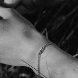 Close-up of a hand wearing a handcrafted 18k recycled gold bracelet in a natural setting.
