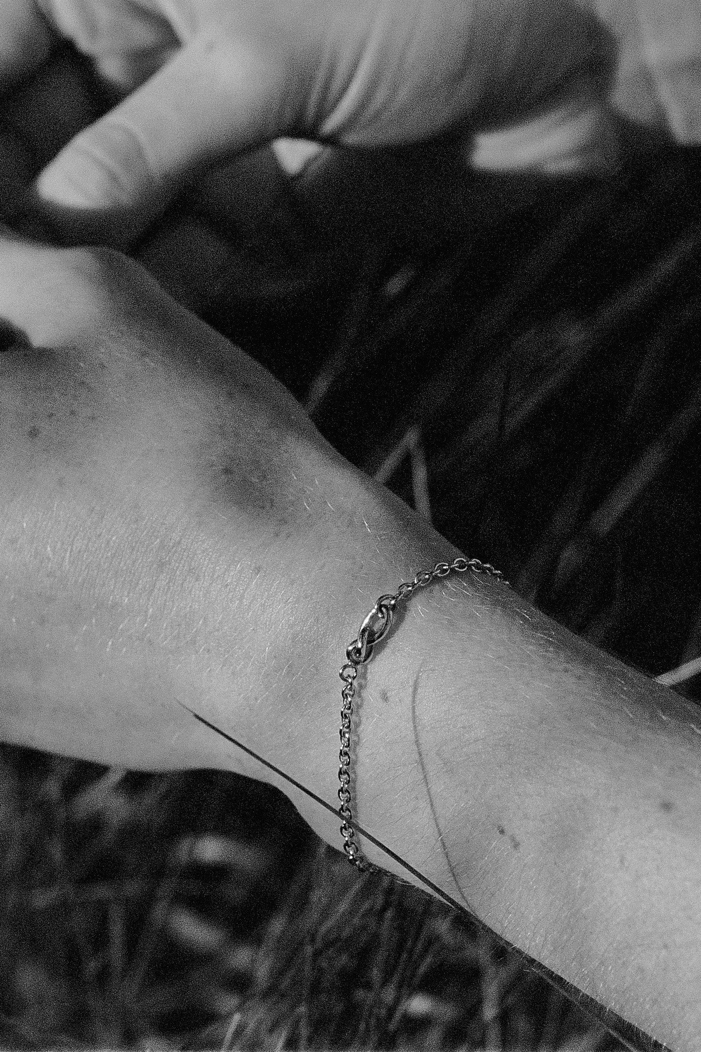 Close-up of a hand wearing a handcrafted 18k recycled gold bracelet in a natural setting.