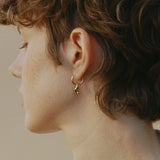 Model wearing SINUOSA hoops in 18k recycled gold, showcasing organic design and craftsmanship from Basel, Switzerland.