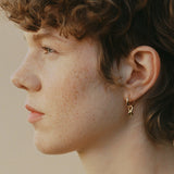 Profile view of a person wearing SINUOSA hoops in 18k recycled gold, showcasing sustainable and handcrafted jewelry.