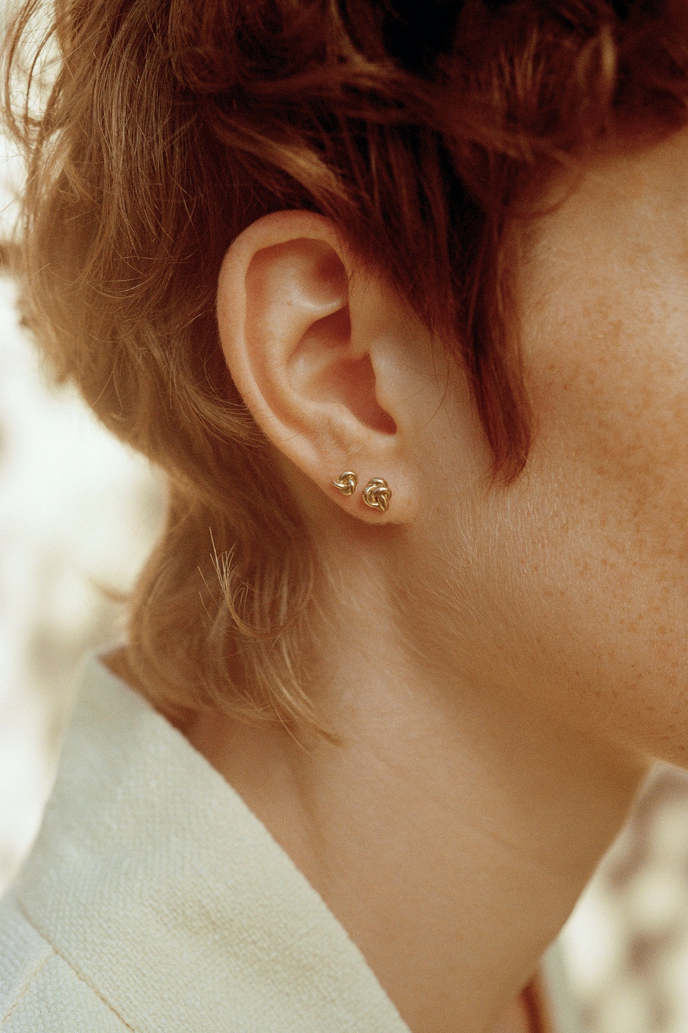 Close-up of a model wearing handcrafted 18k recycled gold studs, showcasing sustainable jewelry designed in Basel, Switzerland.