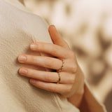Close-up of a hand wearing AGAPI rings, handcrafted from 18k recycled gold in Basel, Switzerland.