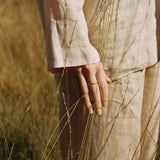 A close-up of a hand holding grass in a field, showcasing natural textures and earthy tones.