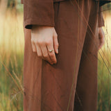 Handcrafted TWINE ring in 18k recycled gold worn on a hand in Basel Switzerland, set against a natural outdoor backdrop.