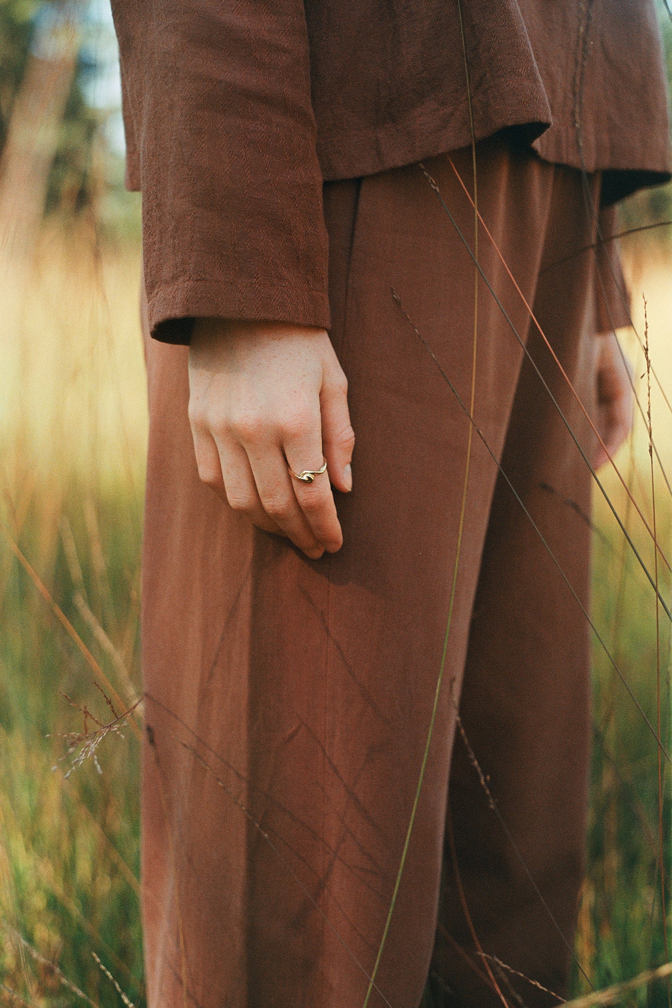 Handcrafted TWINE ring in 18k recycled gold worn on a hand in Basel Switzerland, set against a natural outdoor backdrop.