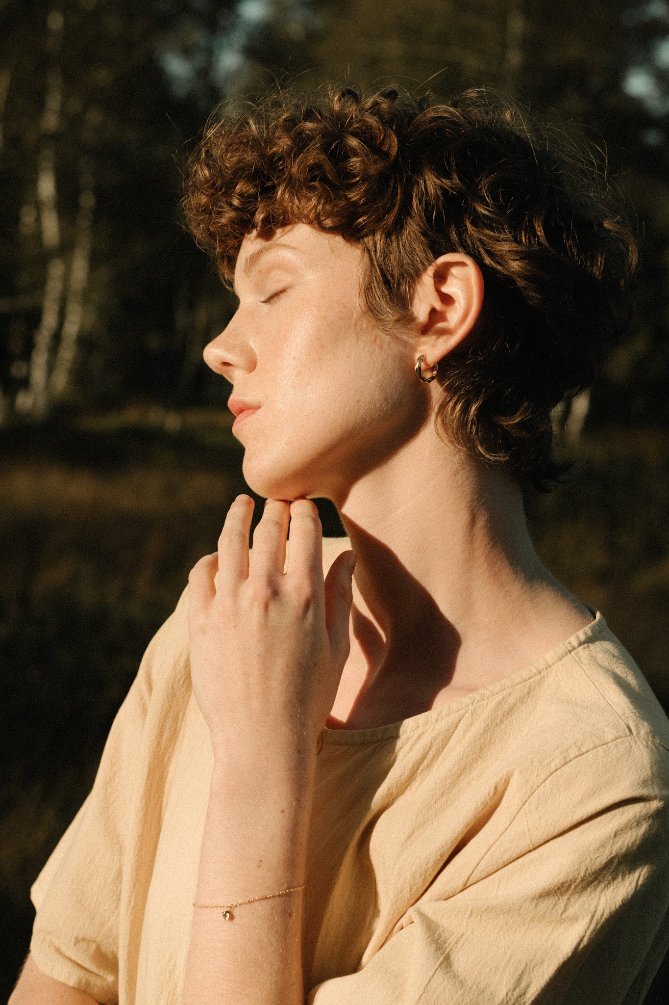Model showcasing TOVE bracelet made of 18k recycled gold in a sunlit outdoor setting in Basel, Switzerland.