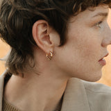 Model showcasing AGAPI hoops made of 18k recycled gold, highlighting sustainable jewelry from Basel, Switzerland.