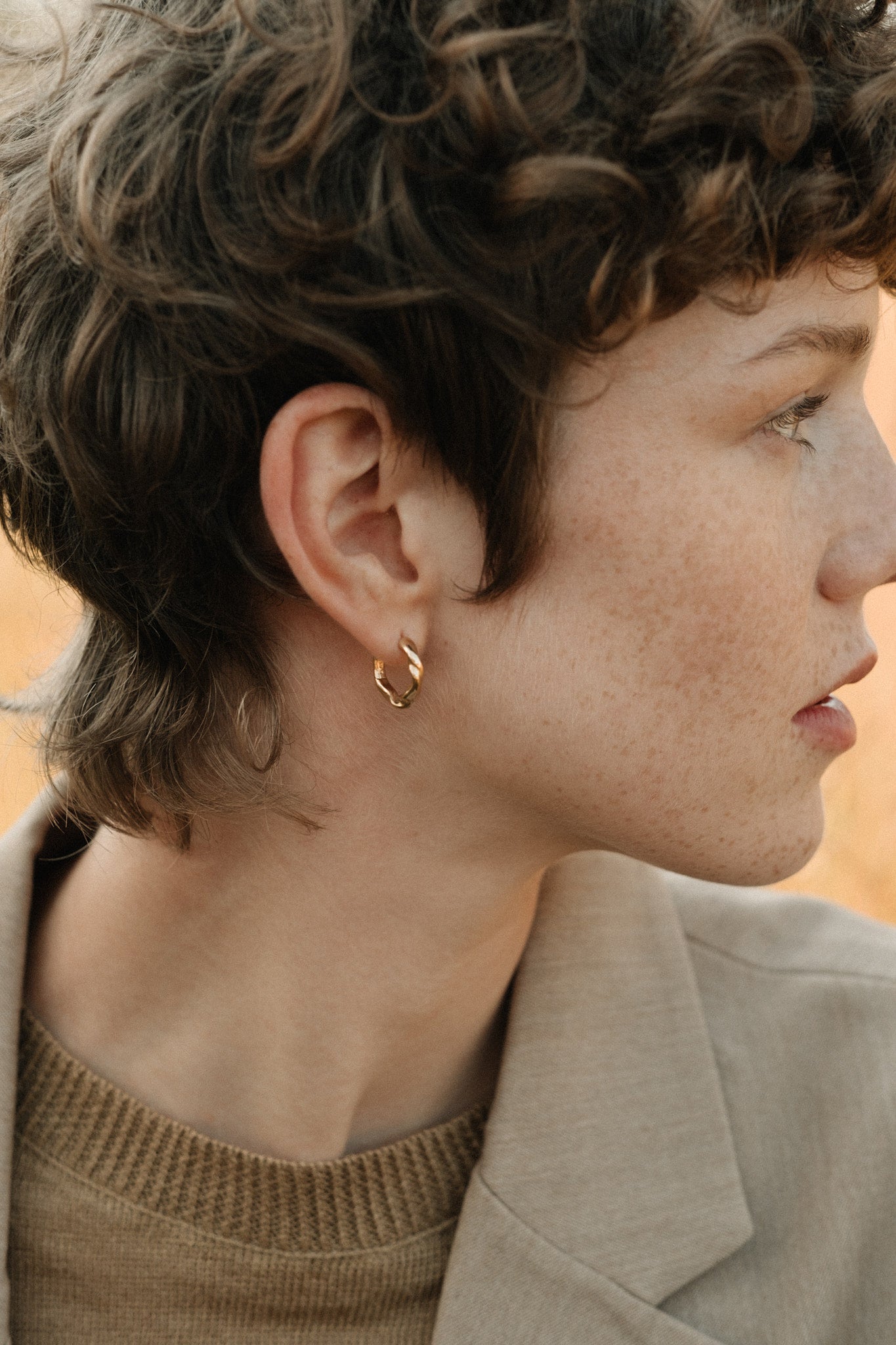 Model showcasing AGAPI hoops made of 18k recycled gold, highlighting sustainable jewelry from Basel, Switzerland.