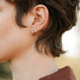 Profile view of a person wearing 18k recycled gold LOA hoops, showcasing their handcrafted design from Basel, Switzerland.