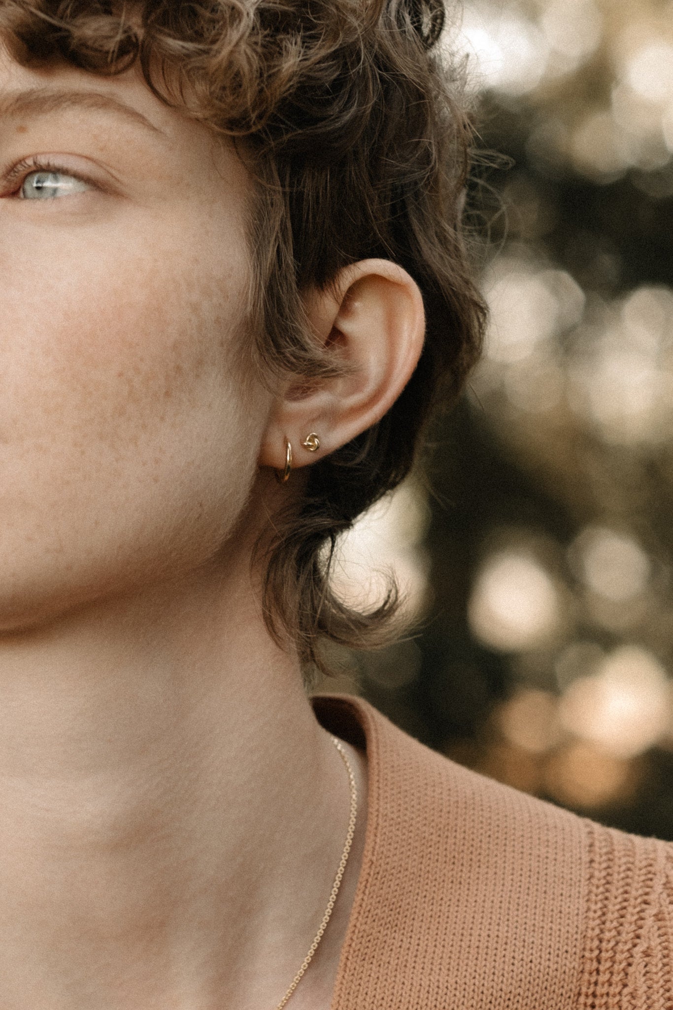 Model showcasing handcrafted 18k recycled gold LOA hoops, highlighting a natural shiny surface in Basel, Switzerland.