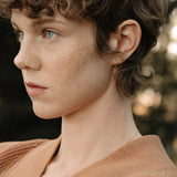 Side profile of a person with curly hair wearing handcrafted 18k recycled gold jewelry.