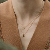 Close-up of a person wearing two layered 18k gold necklaces, showcasing sustainable handcrafted jewelry in Basel.