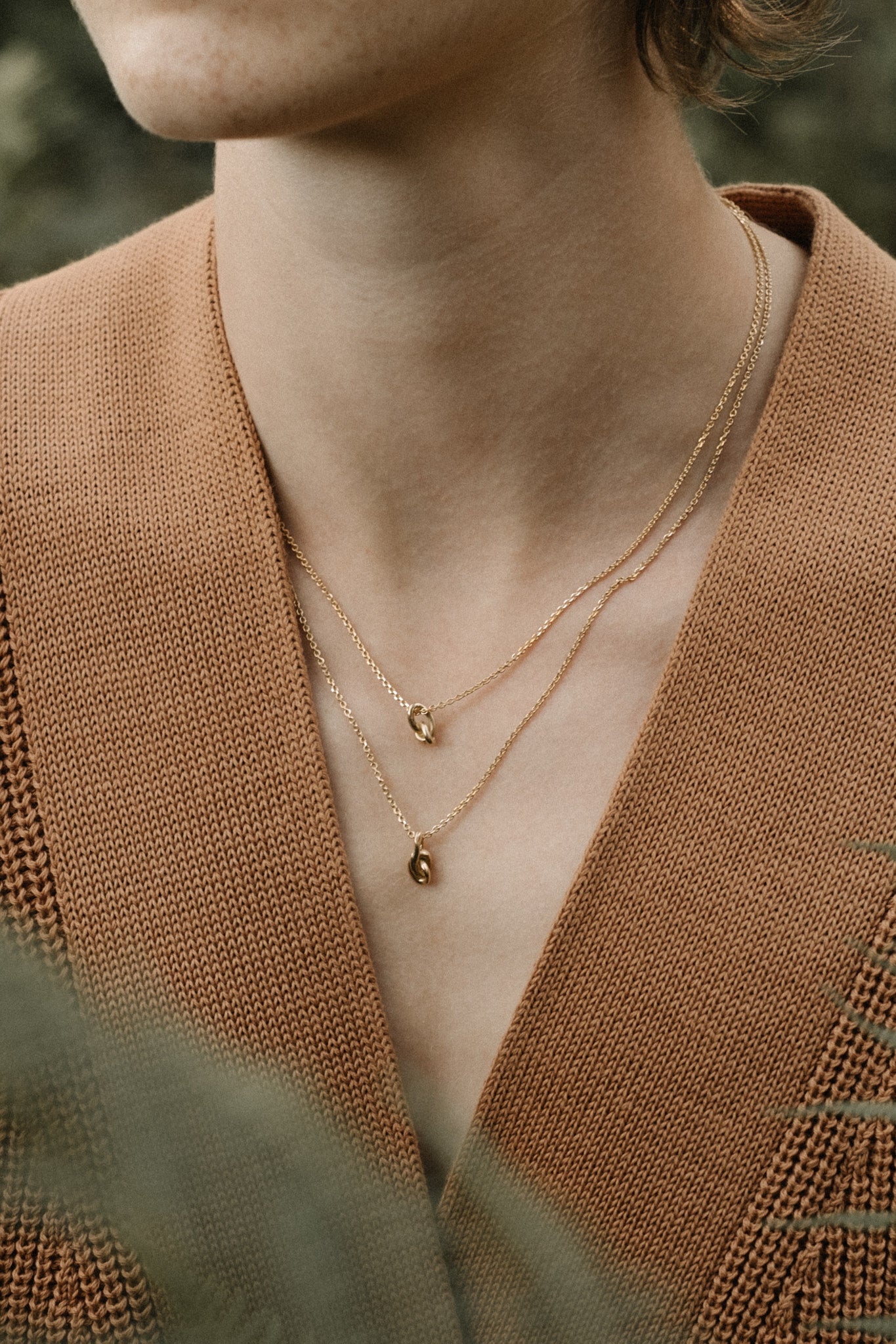 Close-up of a person wearing two layered 18k gold necklaces, showcasing sustainable handcrafted jewelry in Basel.