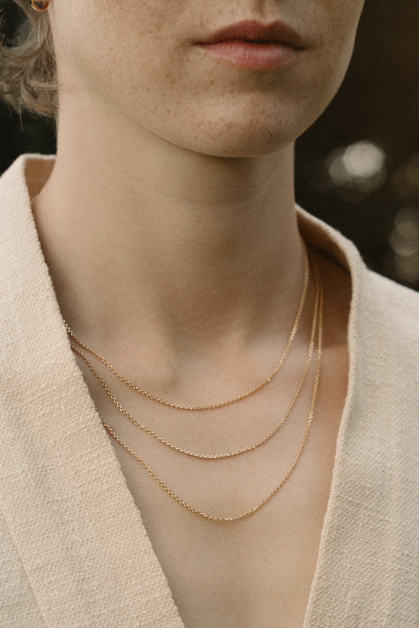 Close-up of a model showcasing layered 18k recycled gold chains, handcrafted in Basel, Switzerland.