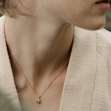 Close-up of a model wearing a TOVE pendant in 18k recycled gold, showcasing handcrafted elegance from Basel, Switzerland.