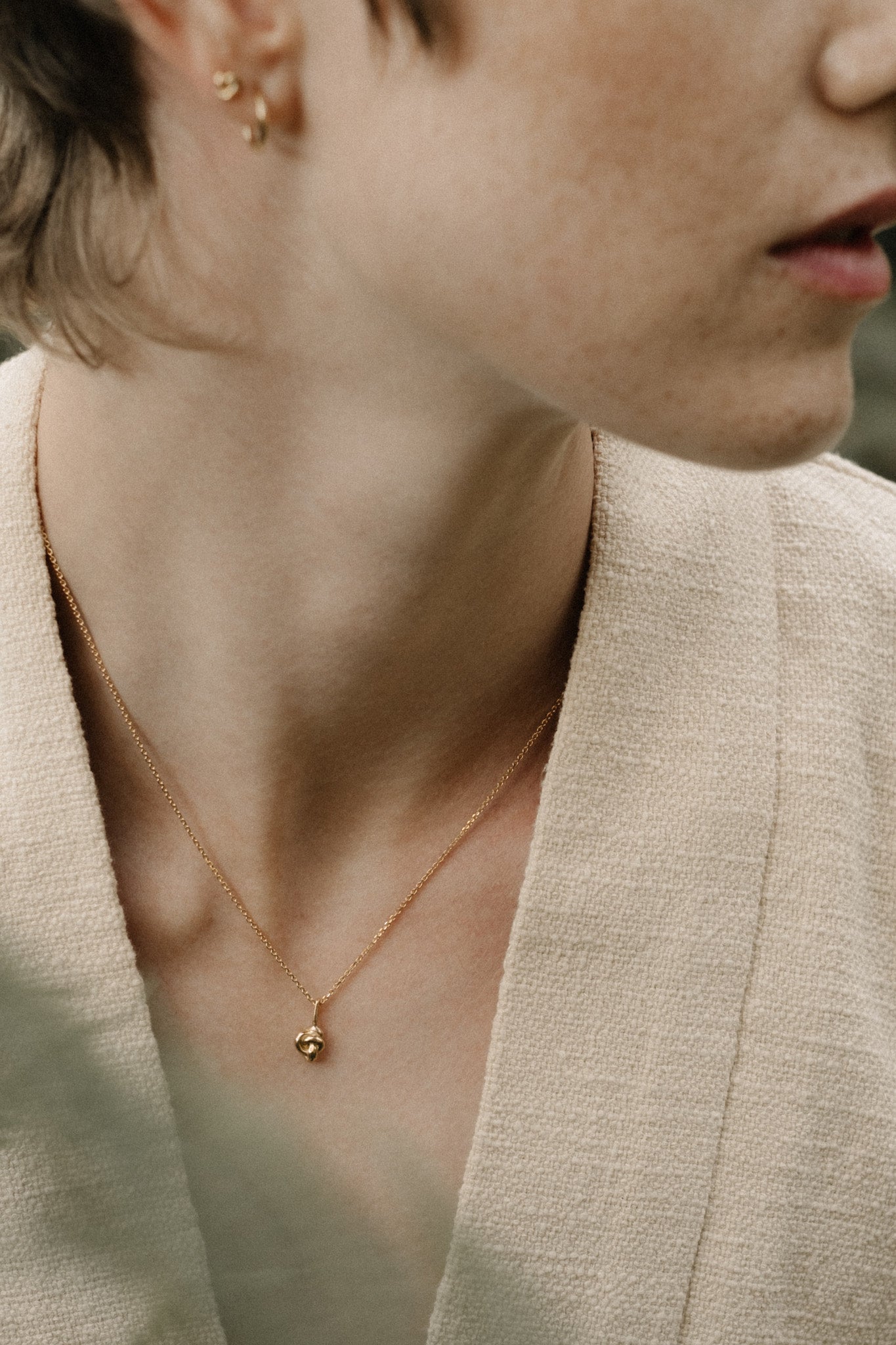 Close-up of a model wearing a TOVE pendant in 18k recycled gold, showcasing handcrafted elegance from Basel, Switzerland.