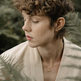 Model wearing handcrafted jewelry, surrounded by ferns, showcasing natural beauty in Basel, Switzerland.