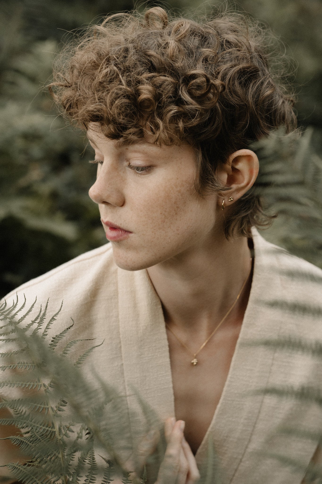 Model wearing handcrafted jewelry, surrounded by ferns, showcasing natural beauty in Basel, Switzerland.
