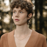 Model wearing TRESSE chain made of 18k recycled gold, showcasing sustainable jewelry in a natural outdoor setting.