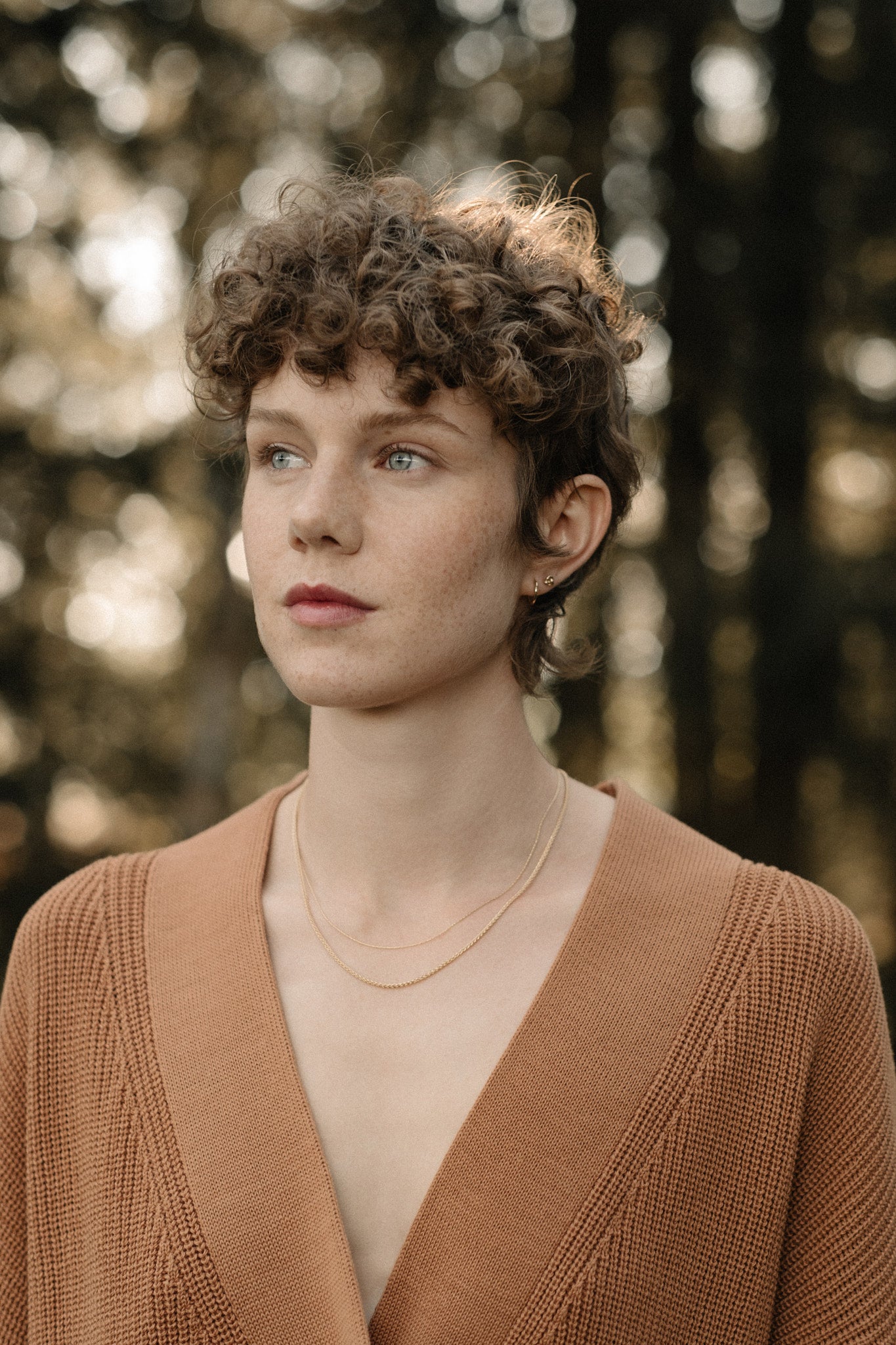 Model wearing TRESSE chain made of 18k recycled gold, showcasing sustainable jewelry in a natural outdoor setting.