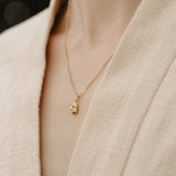 Handcrafted 18k recycled gold TWINE necklace worn on a beige garment, designed in Basel, Switzerland.
