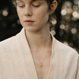 Model wearing a TWINE pendant necklace made of 18k recycled gold, showcasing handcrafted elegance from Basel, Switzerland.