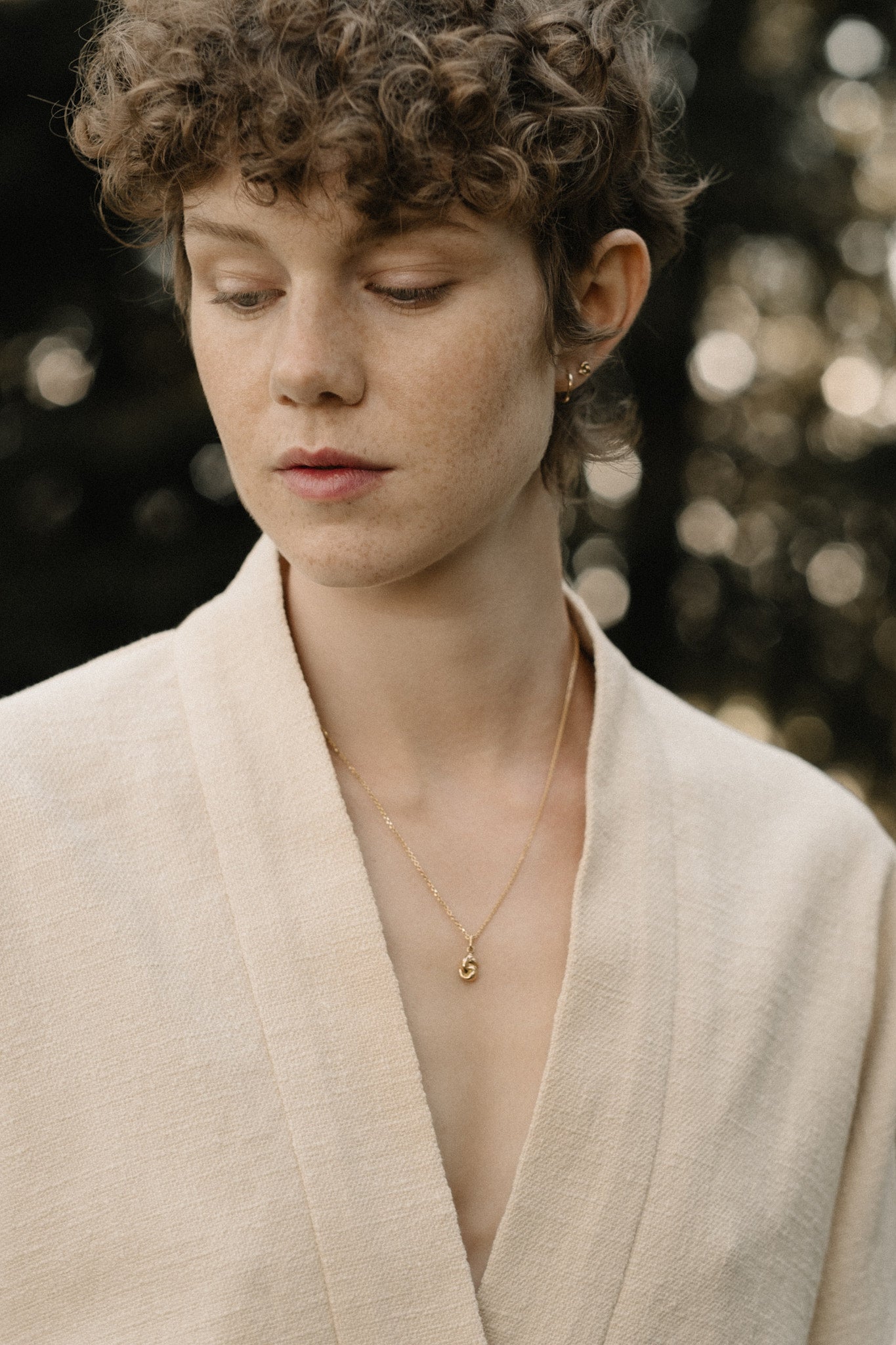 Model wearing a TWINE pendant necklace made of 18k recycled gold, showcasing handcrafted elegance from Basel, Switzerland.