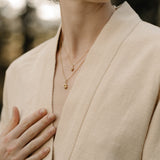 Close-up of a model wearing a beige jacket with layered necklaces featuring organic designs handcrafted in Basel, Switzerland.