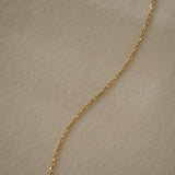 Elegant 18k recycled gold chain on soft fabric, handcrafted in Basel, Switzerland, showcasing organic design and craftsmanship.