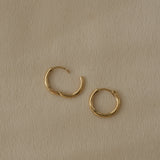 Handcrafted 18k recycled gold hoops in small and medium sizes; organic design from Basel, Switzerland.