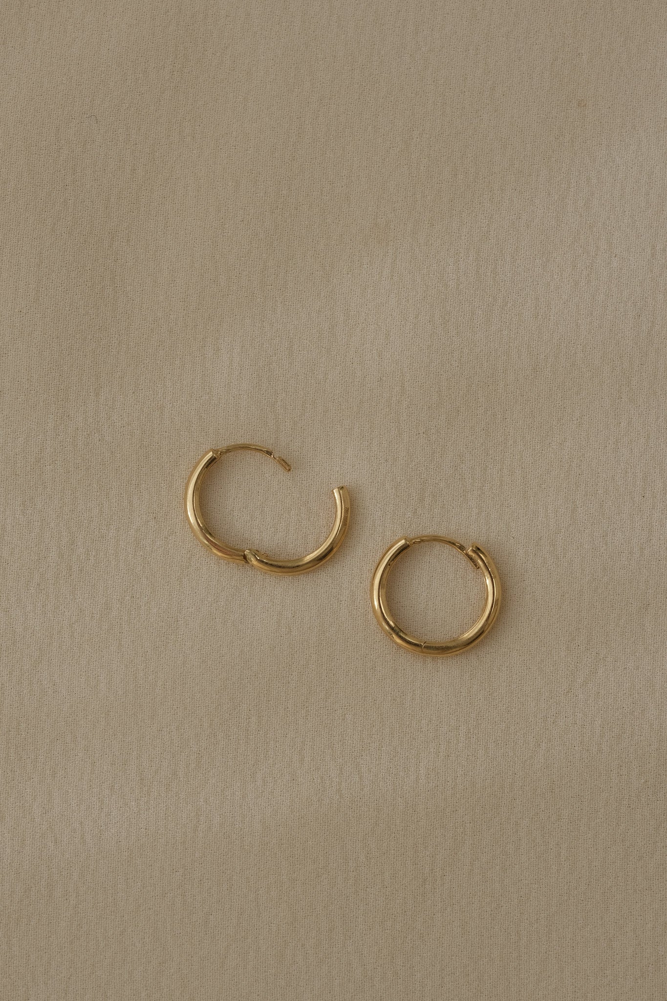 Handcrafted 18k recycled gold hoops in small and medium sizes; organic design from Basel, Switzerland.
