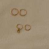 Handcrafted 18k recycled gold hoops in various sizes on soft beige background, made in Basel, Switzerland.