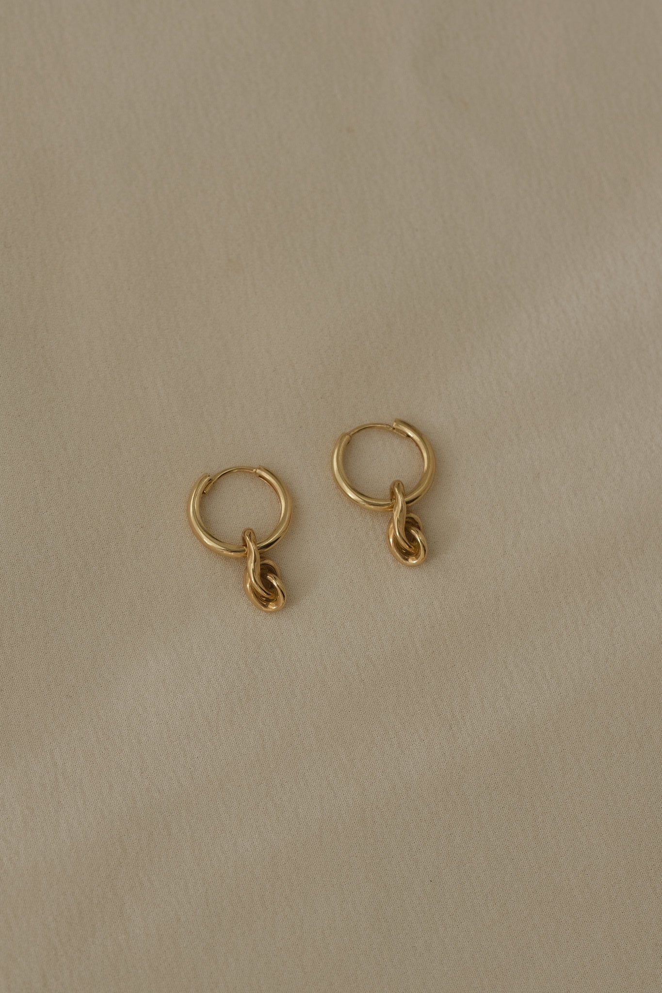 Handcrafted SINUOSA hoops made of 18k recycled gold, featuring a natural shiny surface, designed in Basel, Switzerland.