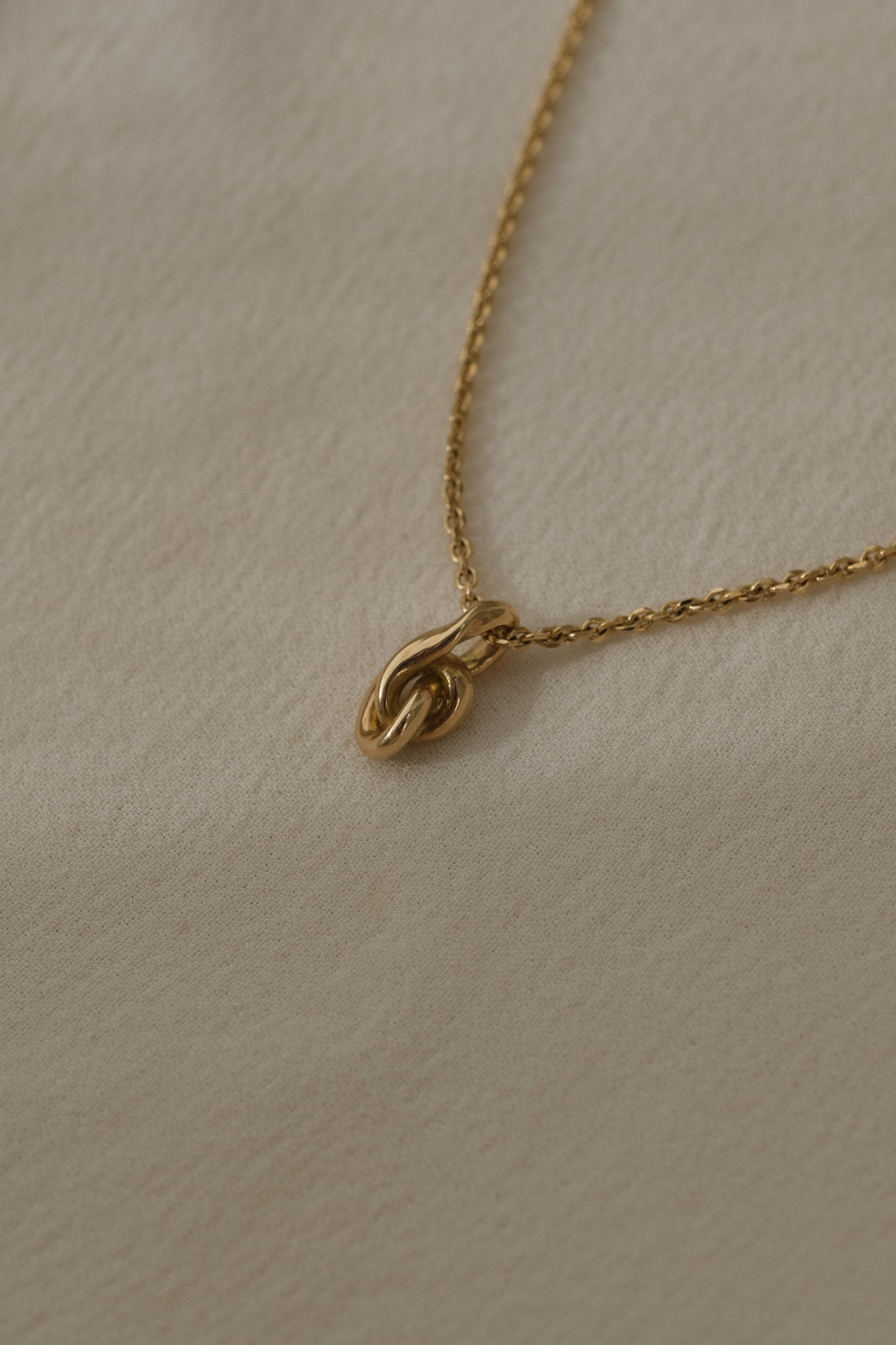 SINUOSA necklace crafted from 18k recycled gold, featuring a unique knot design, handcrafted in Basel, Switzerland.