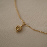 Handcrafted TOVE necklace in 18k recycled gold with a unique knot pendant, designed in Basel, Switzerland.