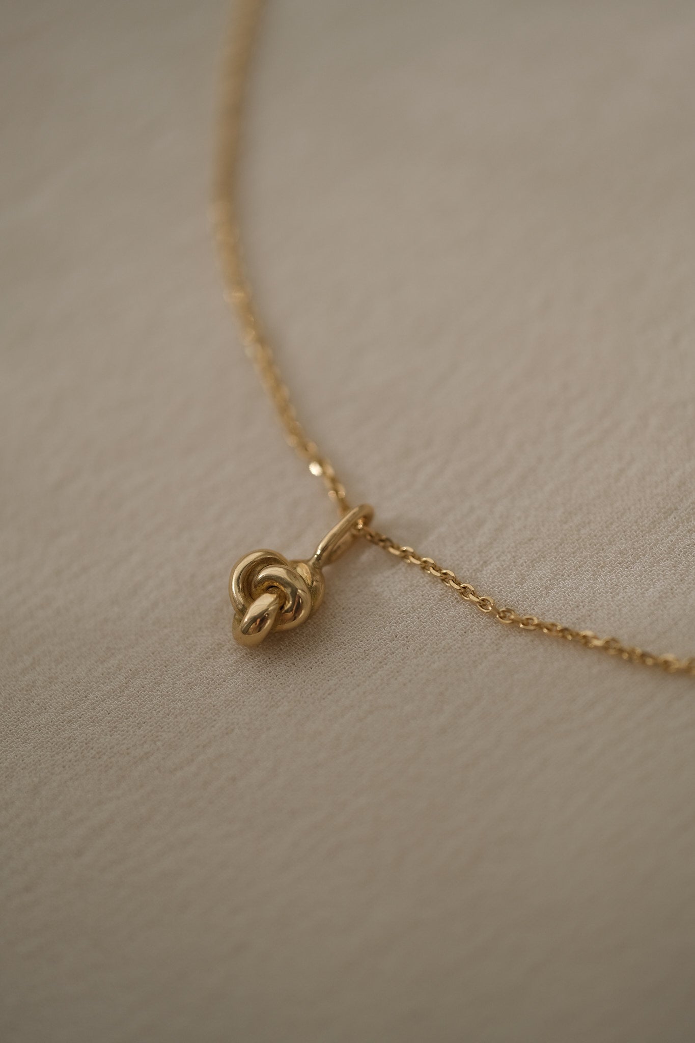 Handcrafted TOVE necklace in 18k recycled gold with a unique knot pendant, designed in Basel, Switzerland.