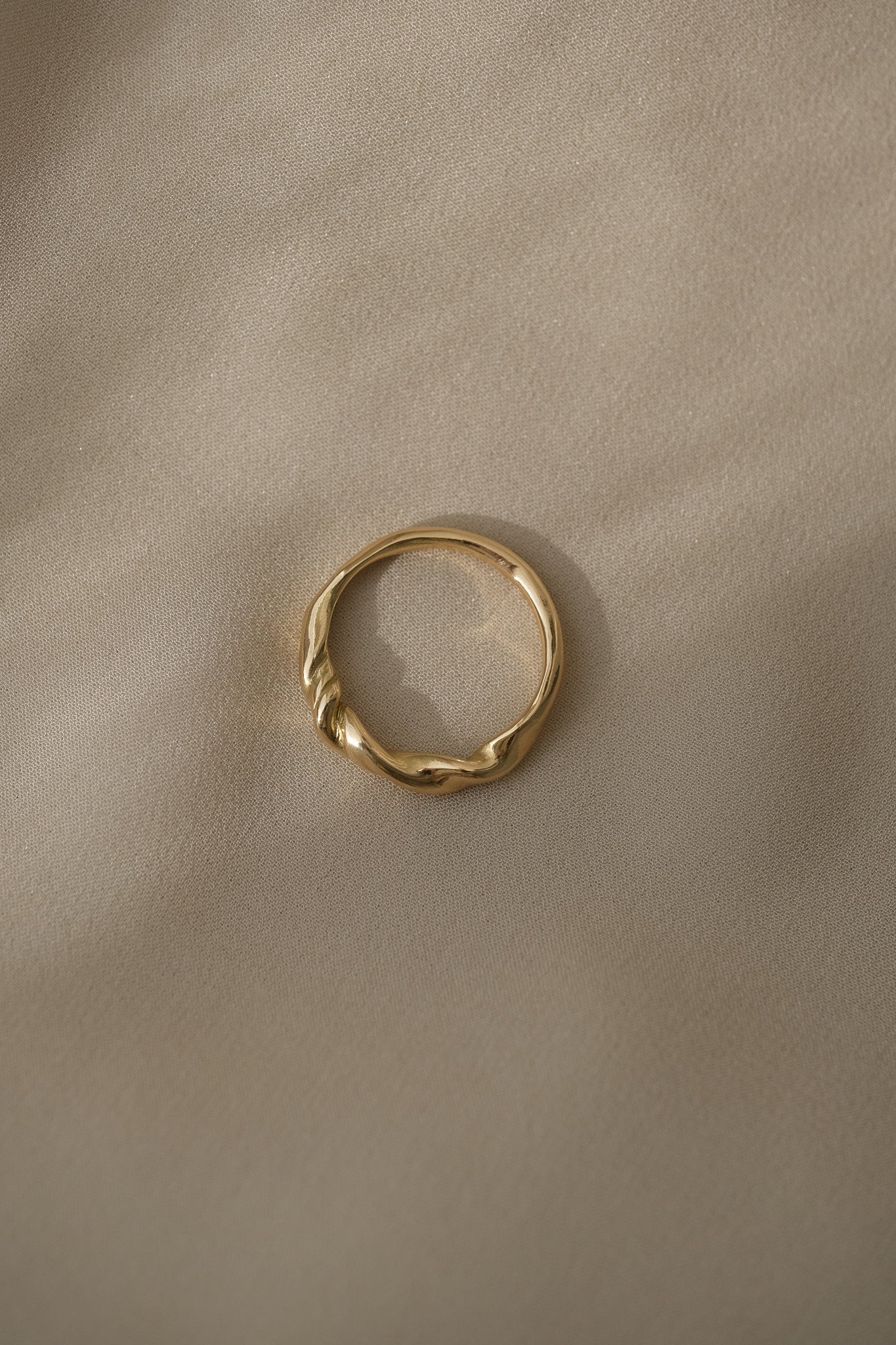 AGAPI 18k recycled gold ring handcrafted in Basel, Switzerland, featuring a natural shiny surface on a soft fabric backdrop.