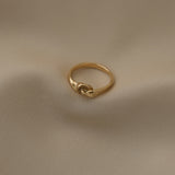 Handcrafted TWINE ring in 18k recycled gold, showcasing an organic design on a soft fabric background.
