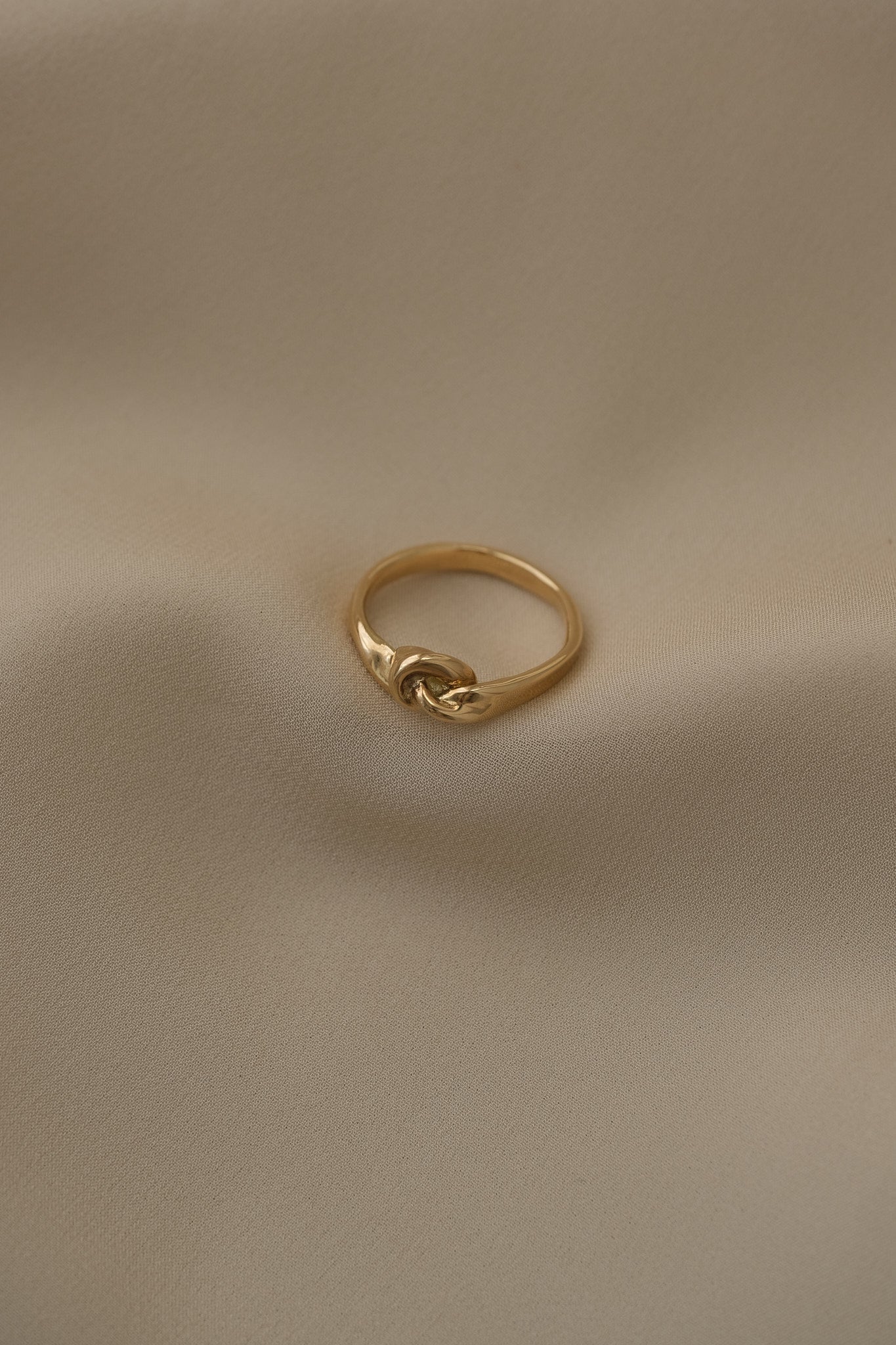 Handcrafted TWINE ring in 18k recycled gold, showcasing an organic design on a soft fabric background.