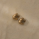 CLOUD earrings in recycled gold, ethically handcrafted, showcasing sustainable jewelry design on sandy surface.