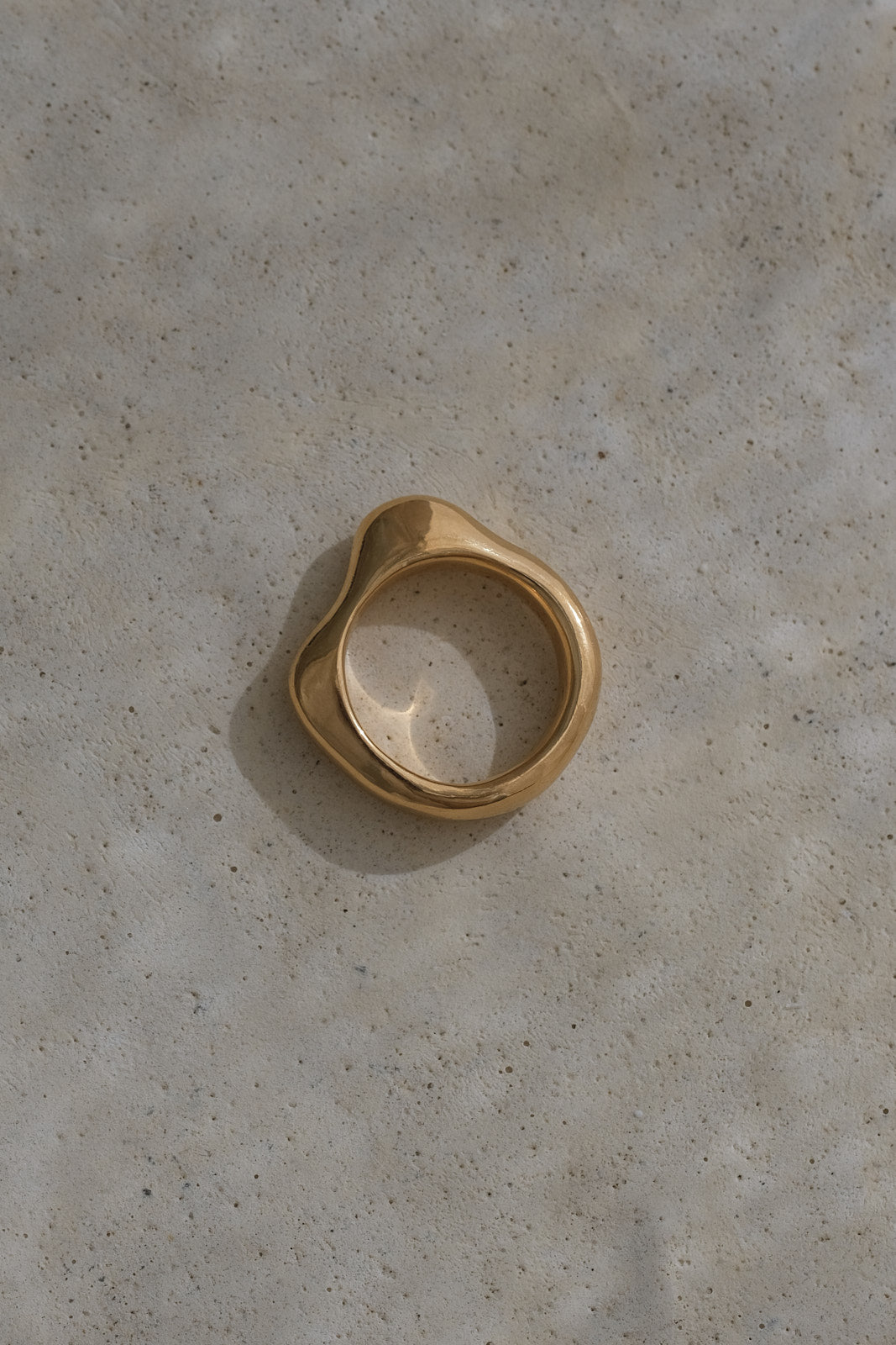 DUNA ring crafted from recycled gold, showcasing an organic shape on a natural stone surface. Ethical handmade jewelry.