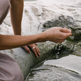 Person wearing a DUNA ring, interacting with water, showcasing sustainable and ethical jewelry design.