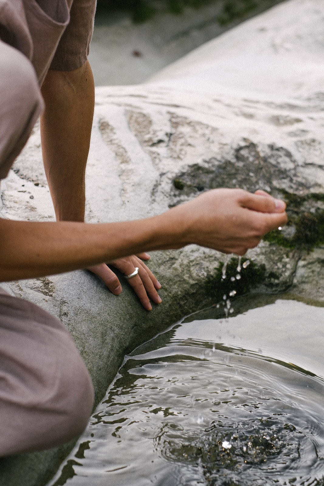 Person wearing a DUNA ring, interacting with water, showcasing sustainable and ethical jewelry design.
