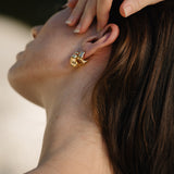 Elegant woman wearing FLUID earrings, handmade from sustainable materials in recycled gold and silver.