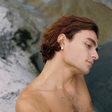 Profile view of a man wearing ethical FLUID earrings made of recycled gold and silver, showcasing handmade craftsmanship.