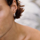 Close-up of a person wearing FLUID earrings in recycled silver, showcasing ethical jewelry and sustainable fashion.