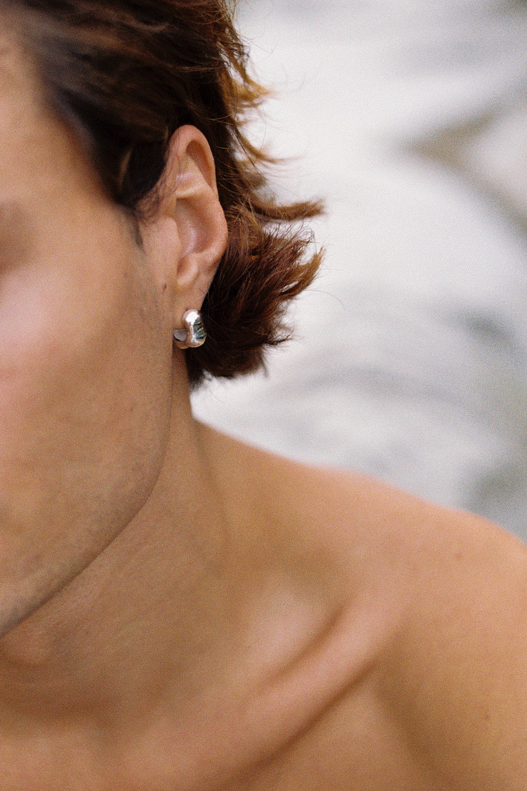 Close-up of a person wearing FLUID earrings in recycled silver, showcasing ethical jewelry and sustainable fashion.