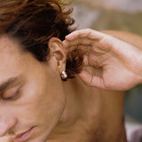 Handmade FLUID earrings in recycled silver worn by a man, showcasing ethical jewelry with a natural shiny surface.