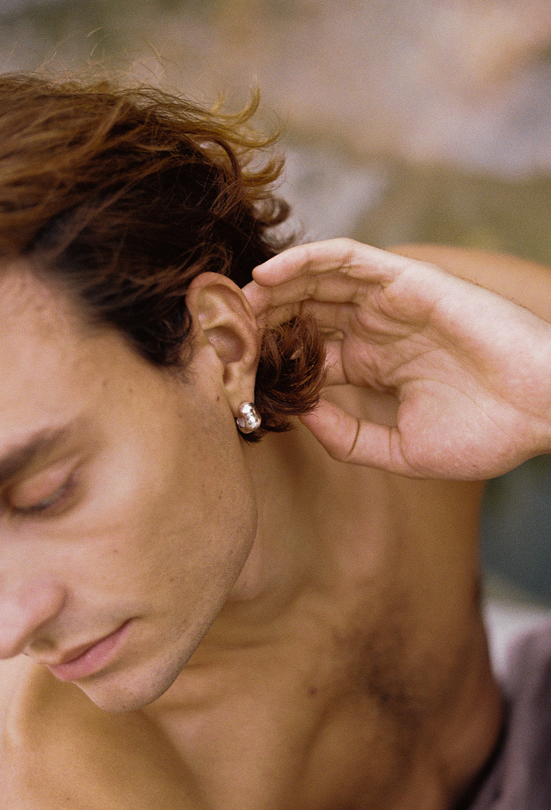 Handmade FLUID earrings in recycled silver worn by a man, showcasing ethical jewelry with a natural shiny surface.